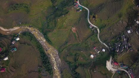 High-aerial-view,-looking-straight-down-over-amazing-rice-terraced-green-misty-mountains-and-windy-river-and-road-in-Sapa,-Vietnam