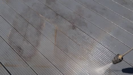 high-pressure-water-jet-cleaner-washing-dirty-black-deck-outside-and-making-a-rainbow-with-the-vapor