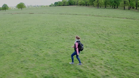 Aerial-view-of-a-woman-running-with-a-backpack-on-for-a-short-distance,-then-stopping-to-look-behind