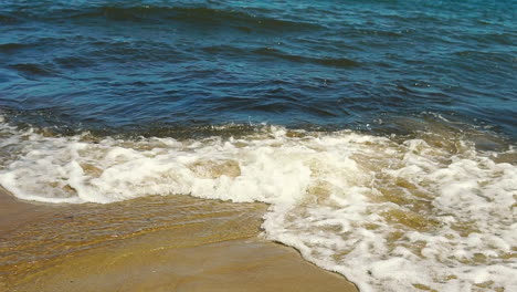 Blick-Auf-Die-Küste,-Schaum-Aus-Wasser-In-Den-Sand-Gegossen,-Sand-Und-Wasser-An-Der-Küste