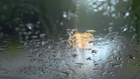 Defocused-headlights-drive-by-a-parked-car-with-a-rain-streaked-windshield