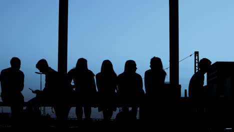 Silhouettes---Group-of-people-is-sitting-together-at-evening-light---slow-motion