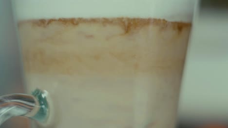 Kaffee-Latte-In-Glasschichten-Vermischen-Sich-Mit-Löffel-Aus-Nächster-Nähe
