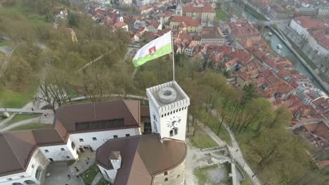 Fly-over-Ljubljana-castle-and-flag,-one-of-the-most-important-landmarks-of-the-city,-Slovenia