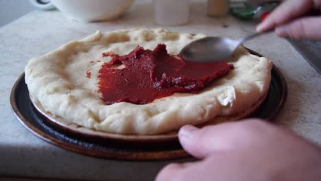 Spreading-the-tomato-paste-on-the-prebaked-pizza-base