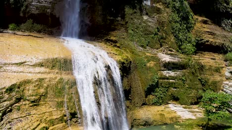Slow-rising-aerial-view-up-of-tropical-Bohol-waterfall,-surrounded-by-lush,-tropical-green-foliage---paradise-woodland-green-trees