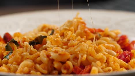 Sticking-a-silver-fork-into-fusilli-pasta-with-tomato-sauce,-lifting-it-up-and-stretching-melted-mozarella-cheese,-mouthwatering-shot-on-motorized-slider-from-left-to-right