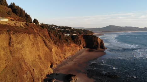 Drone-flies-around-cliff-at-the-beach-at-golden-hour
