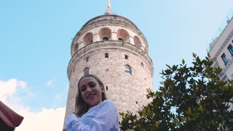 Cámara-Lenta:-Atractiva-Joven-Hermosa-Posa-Frente-A-La-Torre-De-Galata,-Un-Hito-Popular-En-Estambul,-Turquía
