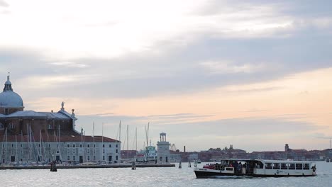Tracking-shot-of-boat-passing-by-church-of-San-Giorgio-Maggiore-in-Venice,-Italy-at-sunrise