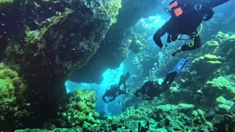 Divers-swimming-into-the-coral-cave