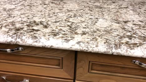 Granite-countertop-made-of-natural-stone-in-grown-and-white-colors-on-maple-kitchen-wood-cabinets