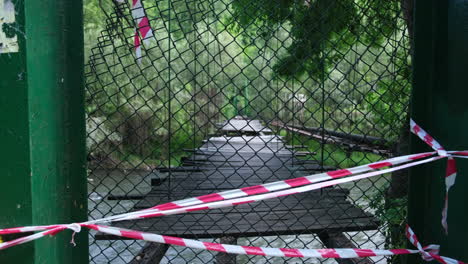 Alte-Geschlossene-Holzbrücke-Mit-Fehlenden-Latten-über-Einen-Fluss-Im-Wald
