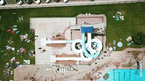 Drone-Shot-directly-above-a-double-twisty-waterslide-at-an-outdoor-public-pool