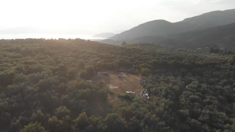 AERIAL-drone-footage-of-mountain-forest,-green-trees-and-an-outdoor-music-live-stage-sea-at-background-at-Pelion-Greece