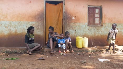 Eine-Familie-Afrikanischer-Frauen-Und-Kinder,-Die-Vor-Ihrem-Kleinen-Haus-In-Einem-Ländlichen-Afrikanischen-Dorf-Lachen-Und-Reden