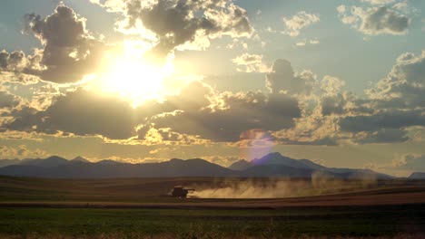Combine-harvester-in-rural-Colorado,-against-a-background-of-mountains-and-sunset