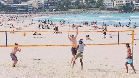 Eine-Gruppe-Von-Vier-Freunden-Spielt-An-Einem-Frühlingstag-Am-Bondi-Beach-In-Sydney,-Australien,-Eine-Partie-Beachvolleyball