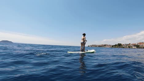 Young-woman-doing-stand-up-paddling-on-a-turquoise-water