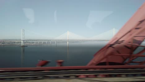 Forth-Road-Bridge-and-Queensferry-Crossing-from-inside-a-moving-train-on-the-Forth-Railway-Bridge
