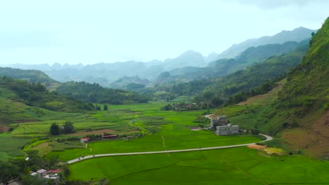 Aerial-pan-left-revealing-lush-rice-farms-nestled-in-a-misty-valley-in-northern-Vietnam