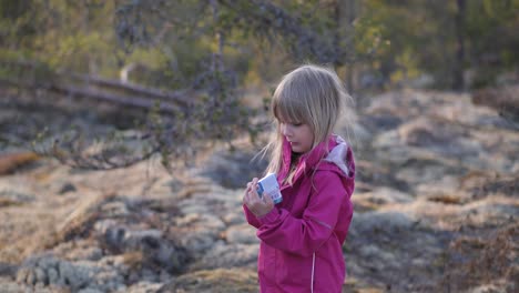 Portrait-of-four-year-old-girl-standing-in-the-forest-holding-new-toy,-static-slow-motion-medium-shot