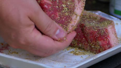 Two-hands-rub-spices-and-salt-into-a-thick-raw-rib-eye-steak-prepping-it-to-be-grilled-in-slow-motion