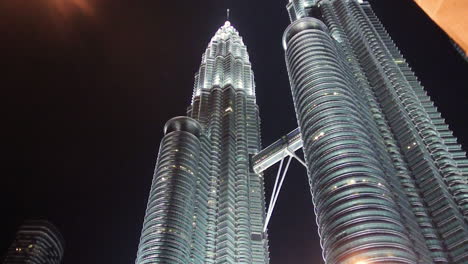 Pan-down-view-of-Singapore-Petronas-Twin-Towers-to-a-busy-street-in-the-night