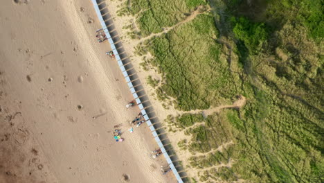 Aerial-Flyover-of-Beach-Huts-on-a-Sandy-Beach-at-Sunset