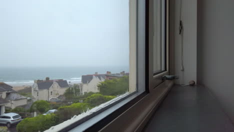 Rain-Flowing-Down-a-Glass-Window-with-an-Ocean-View-in-Slow-Motion