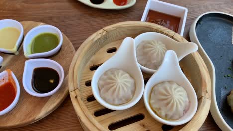 Chinese-Dimsum-neatly-plated-on-a-wooden-table-with-a-colorful-array-of-dipping-sauces