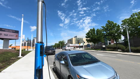 Editorial,-view-of-Chevrolet-electric-car-charging-outside-in-street-beside-the-walk-side,-with-cars-passing-and-beautiful-sky