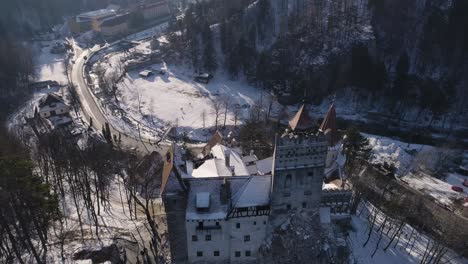 Flyover-the-Bran-Castle-in-Brasov,-Romania-on-a-sunny-afternoon-during-wintertime