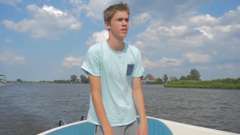 Young-man-is-sailing-a-electric-sloop-in-The-Netherlands-Friesland-in-the-summer-in-Slowmotion