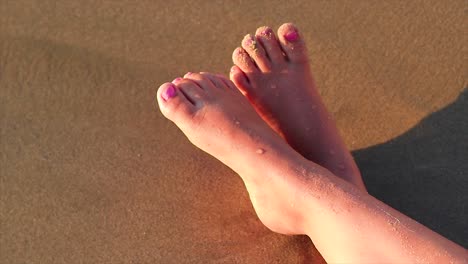 Mädchenbeine-An-Einem-Sandstrand-Mit-Den-Wellen,-Die-Ihre-Beine-Umspülen