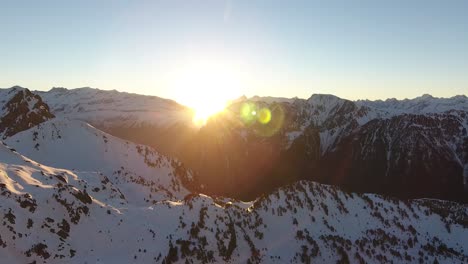 Sunrise-between-mountain-peaks-at-Chamrousse,-France-Alps,-Aerial-dolly-out-shot