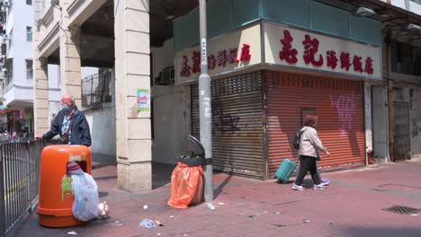 Pedestrians-walk-past-a-closed-business,-a-restaurant,-in-Hong-Kong