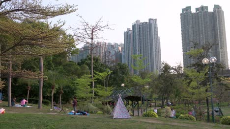 Families-rest-and-enjoy-their-evening-gathering-outdoors-at-a-park-while-social-distancing-still-in-place-due-to-the-Coronavirus-epidemic,-officially-known-as-Covid-19,-in-Hong-Kong