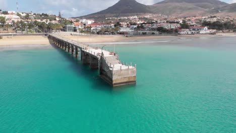 Aerial-circling-over-pier-on-turquoise-sea-waters,-Madeira