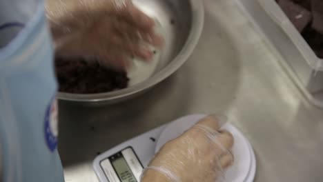 Chocolate-cookie-dough-being-weighed-into-individual-portions-for-baking---isolated