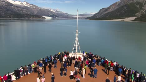 Tourists-on-the-bow-of-a-cruise-ship-in-Glacier-Bay-National-Park-Alaska,-looking-at-the-glacier-and-enjoying-the-landscape