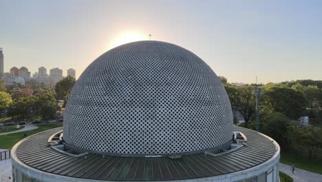 Aerial-dolly-out-of-Galileo-Galilei-Planetarium-in-Palermo-Woods-with-skyline-in-background-at-daytime,-Buenos-Aires
