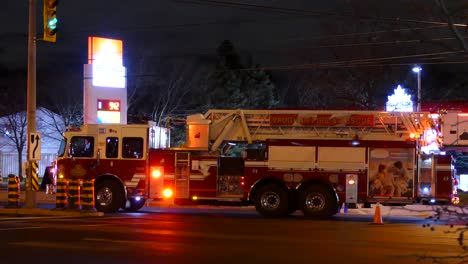 Wide-shot-of-Fire-Department-Fire-Engine-With-Flashing-Light-at-night-parking-in-front-of-service-station,Canada