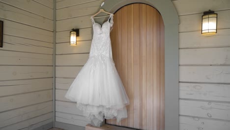 Beautiful-pan-of-a-white-wedding-dress-hanging-on-the-front-porch-of-the-guest-house-cabin-at-the-Le-Belvédère-in-Wakefield,-Quebec,-Canada