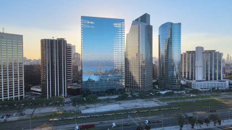 Aerial-of-Paseo-del-Bajo-highway-near-window-glass-Puerto-Madero-skyscrapers-at-golden-hour,-Buenos-Aires
