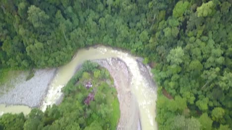 Winding-water-stream-cascading-through-Sumatran-tropical-Forest,-Indonesia---Aerial-fly-over-tilt-up-reveal-shot