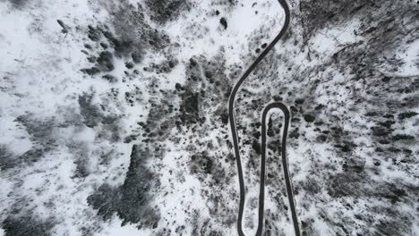 Aerial-dolly-directly-above-mountain-road-car-winter-snow-pine-trees-mist-day