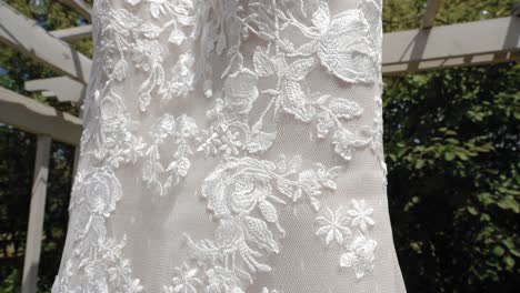 Beautiful-up-close-reveal-of-the-material-design-of-a-fashion-wedding-dress-outside-during-the-summer-at-Strathmere-Wedding-and-Event-center-in-Ottawa,-Canada
