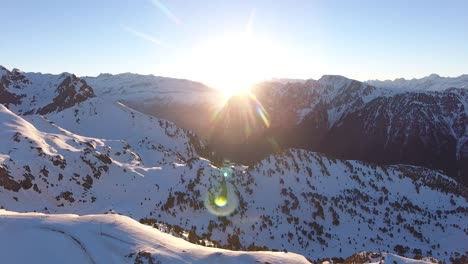 Verschneite-Alpen-In-Der-Region-Chamrousse-In-Frankreich-Mit-Sonnenaufgang-Zwischen-Felsigen-Gipfeln,-Luftaufnahme-Von-Links