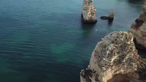 Majestätische-Luftaufnahmen-Der-Felsigen-Küste-Der-Algarve-In-Portugal-Mit-Blick-Auf-Die-Klippen,-Während-Darunter-Möwen-Fliegen